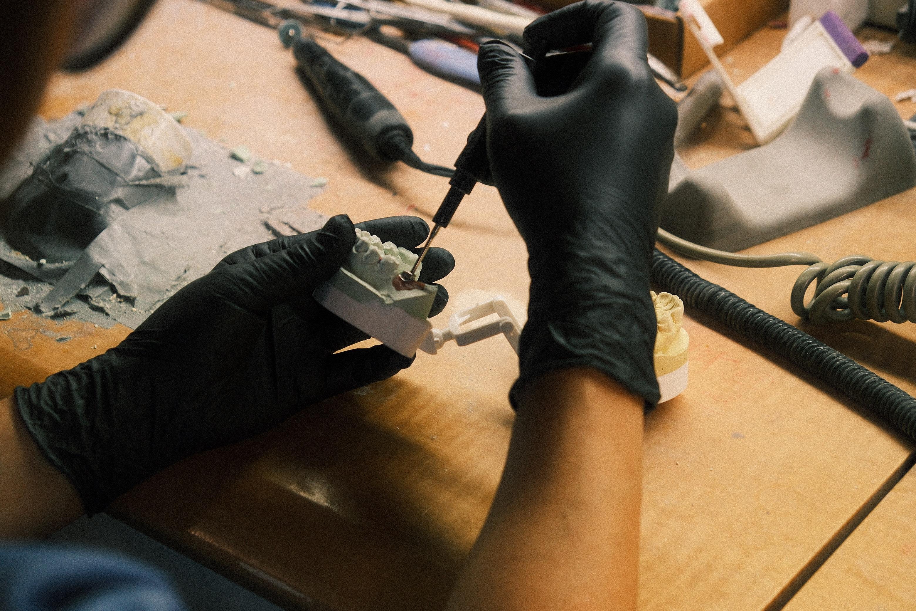 Technician refining an implant crown with a handpiece